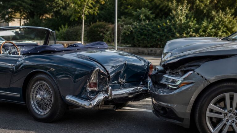 Zwei kollidierte Fahrzeuge mit beschädigten Stoßstangen, ein klassisches Cabrio und ein moderner PKW, Symbolbild für einen Unfall mit einem Cabrio